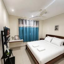 Spacious bedroom featuring queen-sized bed and wall-mounted television