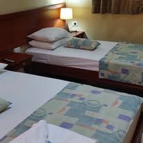 Twin beds in a guest room with timber headboards and beside lamps.