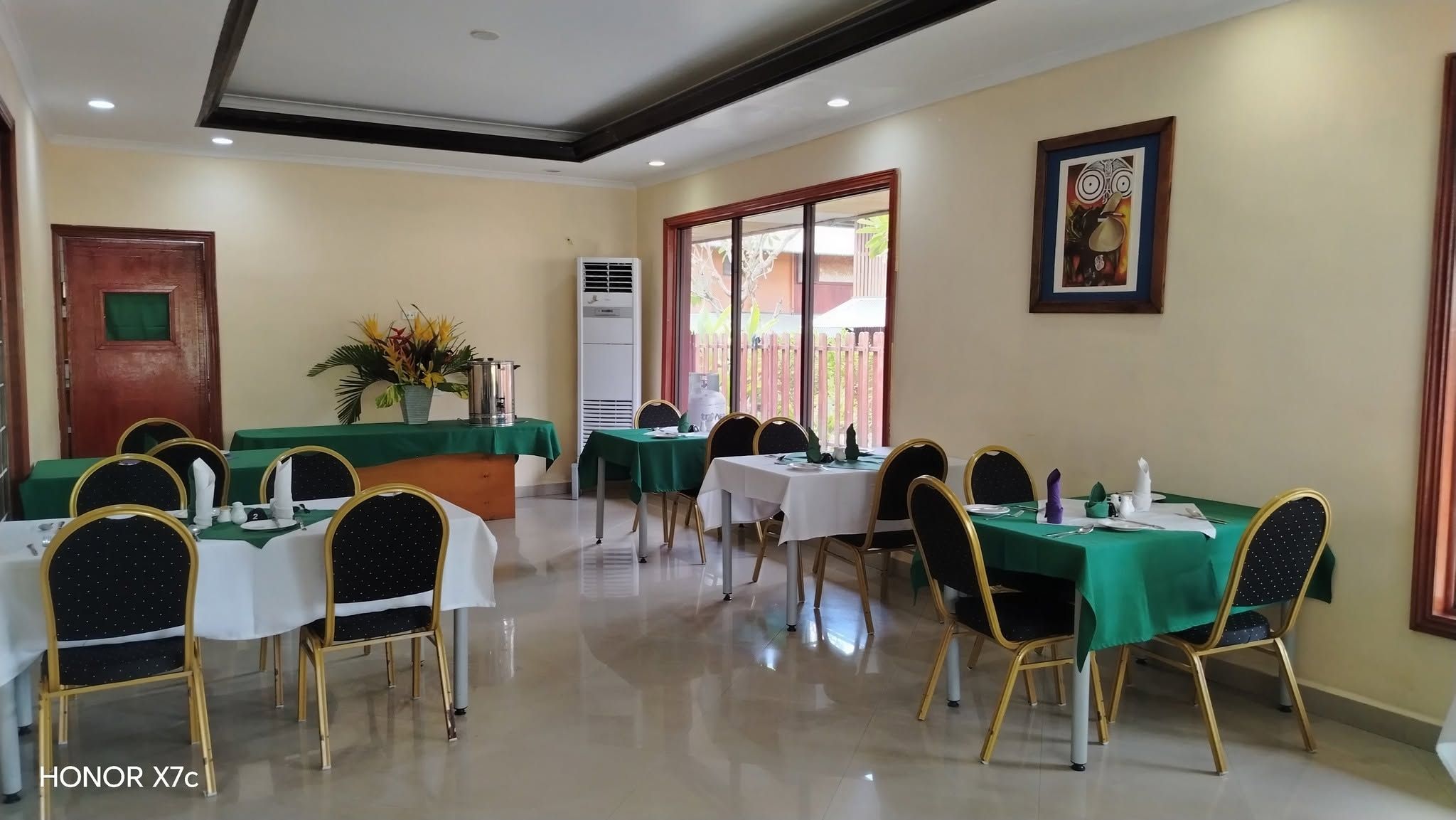 Large dining room with round-back chairs and green and white table linens.