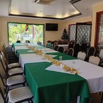 A long banquet table set for an event with green and white linens.