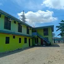 Two-story lime green building exterior with courtyard under a blue sky
