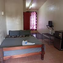 Bedroom featuring a wooden bed frame, television, and small refrigerator