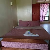 Double bed with pink linens and a white towel in a modest room