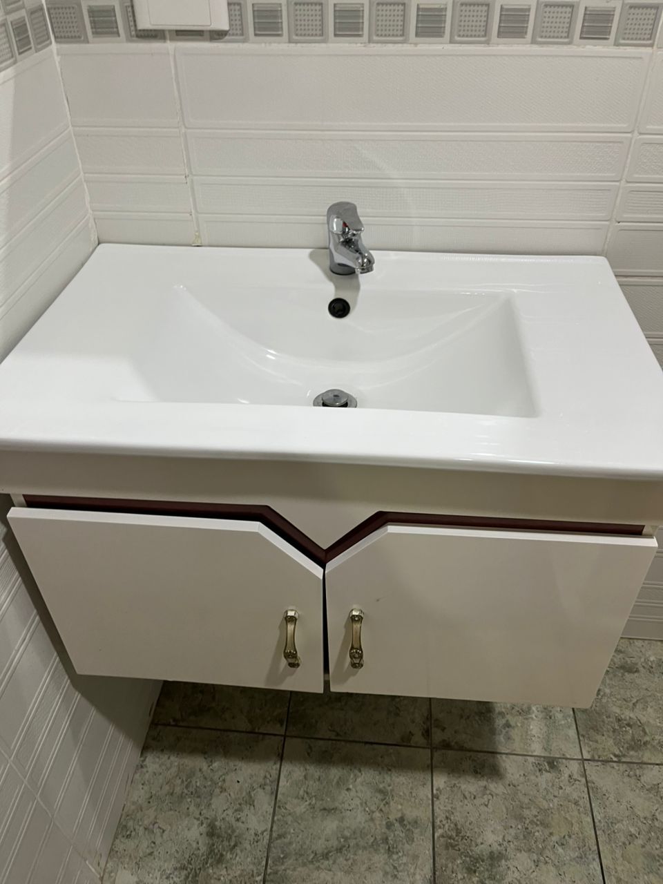 Modern white vanity sink on a tiled bathroom wall.