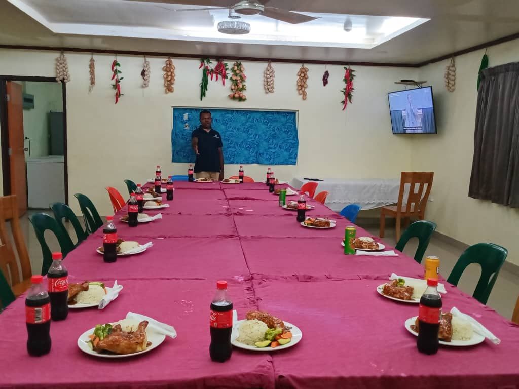 Large communal dining table set with meals and bottled drinks.