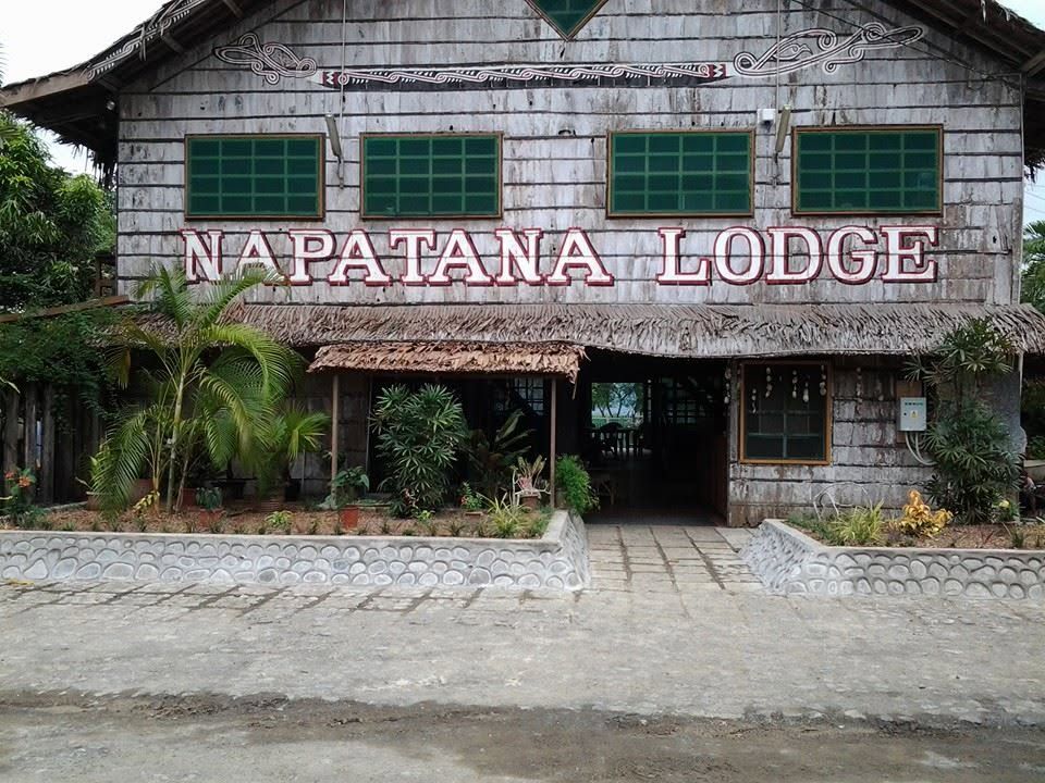 Main front facade of Napatana Lodge featuring traditional wood and thatch design.