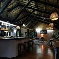 Indoor bar and dining area with high vaulted ceilings and woven lighting fixtures.