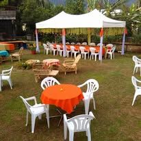 Outdoor events setup with a marquee tent and dining tables on the lawn.