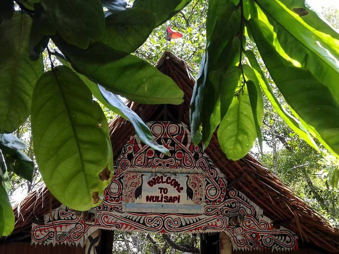 Traditional thatched roof entrance with decorative tribal painted motifs.