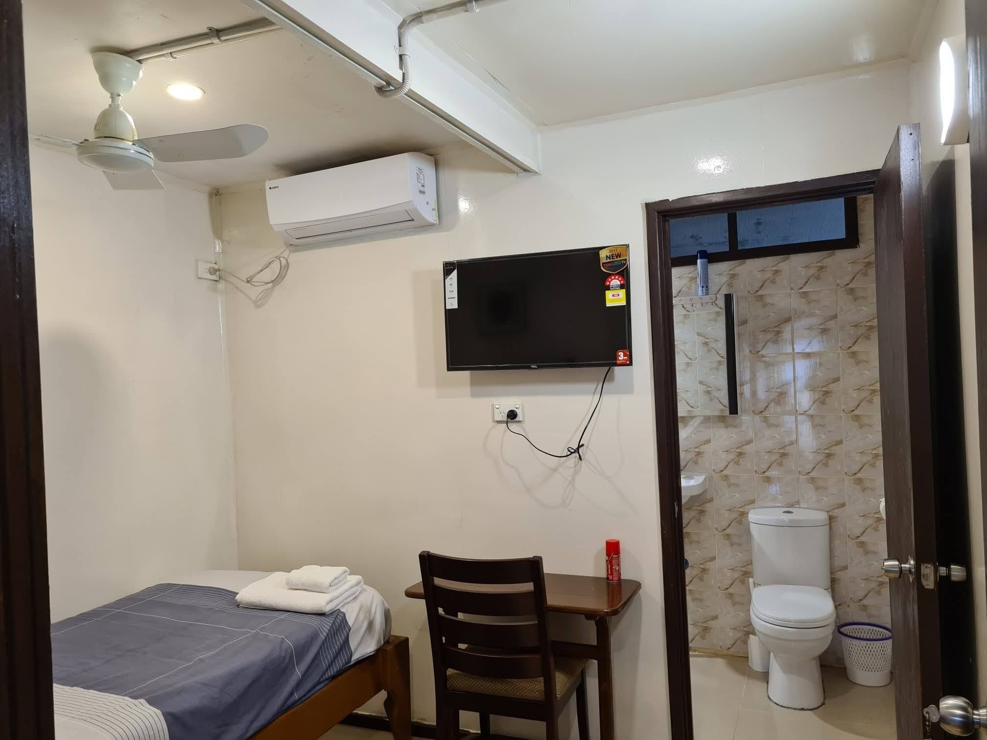 Single bed room with television, desk, and attached bathroom.