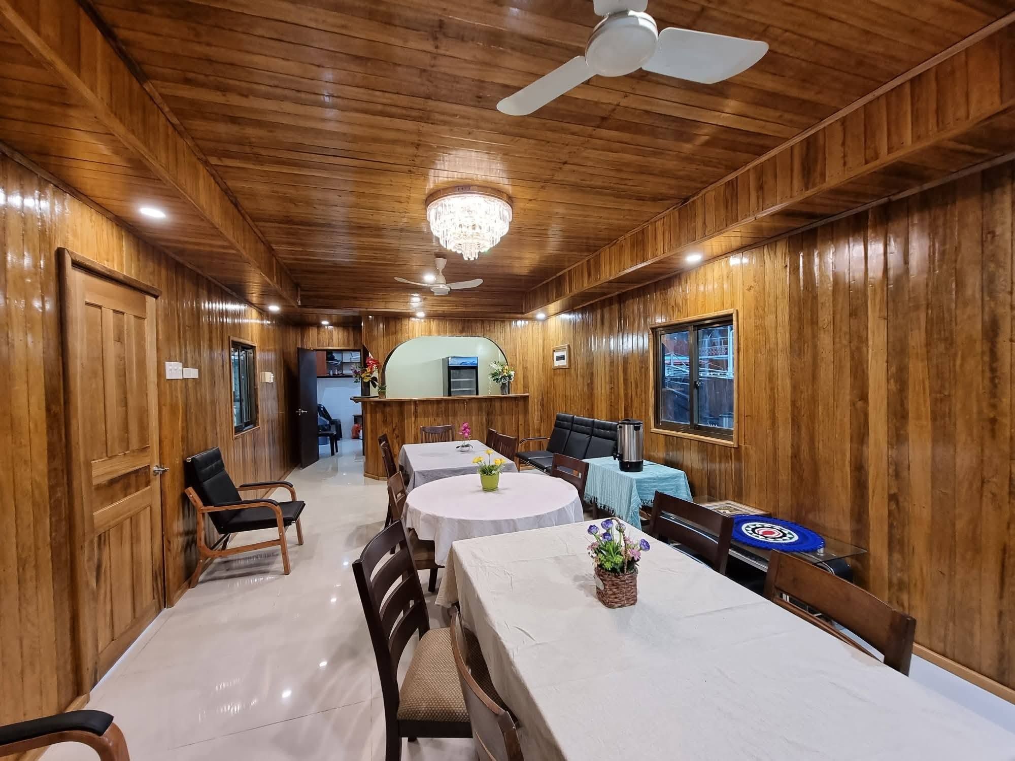 Spacious dining area with polished wooden walls and multiple tables.
