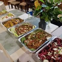 Catering trays with assorted local dishes served in the dining hall.