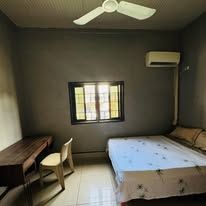 Guest room with a double bed, wooden desk, chair, and air conditioning unit.