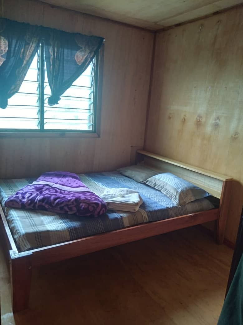 Guest bedroom featuring a wooden bed frame and wood panel walls.