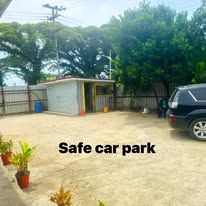 Flat off-street parking area surrounded by trees and a perimeter fence.
