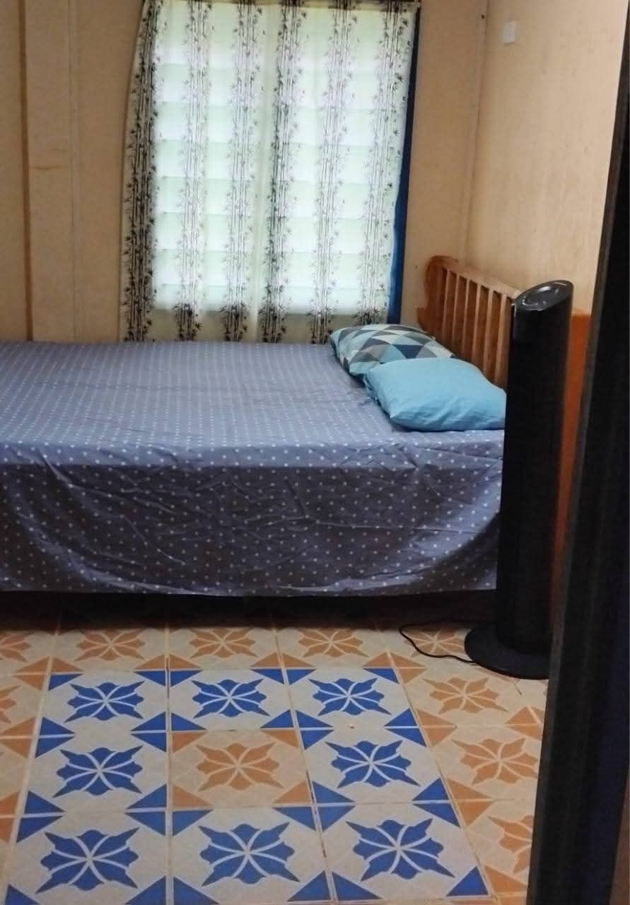 Guest bedroom with a queen bed, tower fan, and patterned floor tiling.
