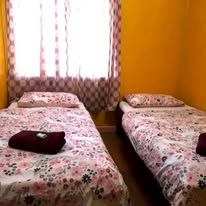 Twin beds with floral patterned linens and dark towels in a yellow room.