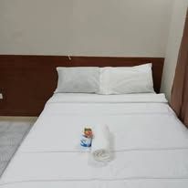 Guest bed with white linens and prepared towel set.