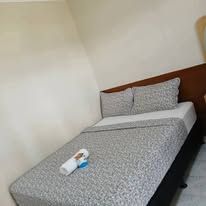 Single bed featuring a grey patterned duvet in a bright room.