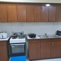 Kitchenette with wooden cabinetry, stove, oven, and double sink.