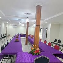A spacious conference room with long tables covered in purple cloths.