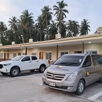 Building exterior and parking area with palm trees in background.