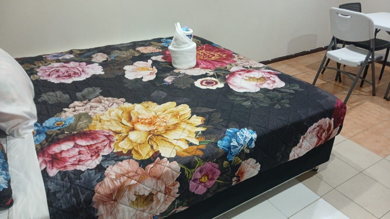 Bed with floral print bedding and a small dining setup nearby