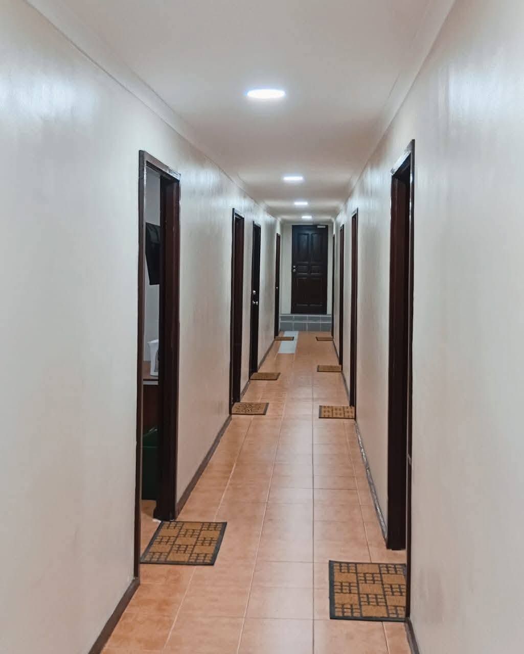 Tiled indoor corridor with room entrances and door mats