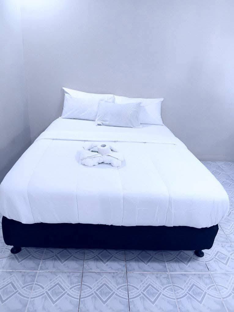 Brightly lit guest room with white bedding and tiled flooring.