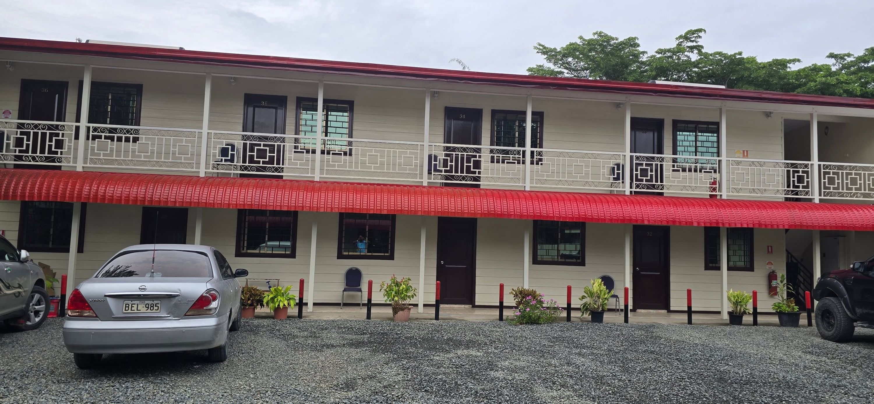 Wide shot of the guest house facade with red awnings and parking area.