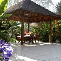 Thatched roof gazebo with a table and chairs in the garden