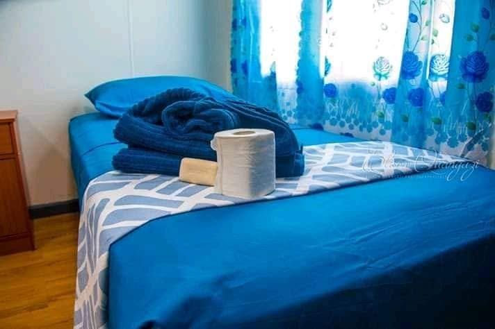 Close-up of a single bed with blue linens and complimentary towels.