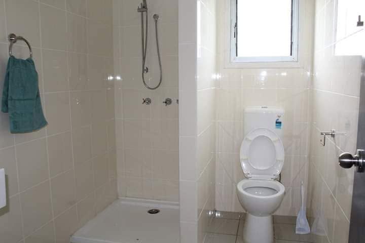 Clean white tiled bathroom featuring a walk-in shower and toilet.