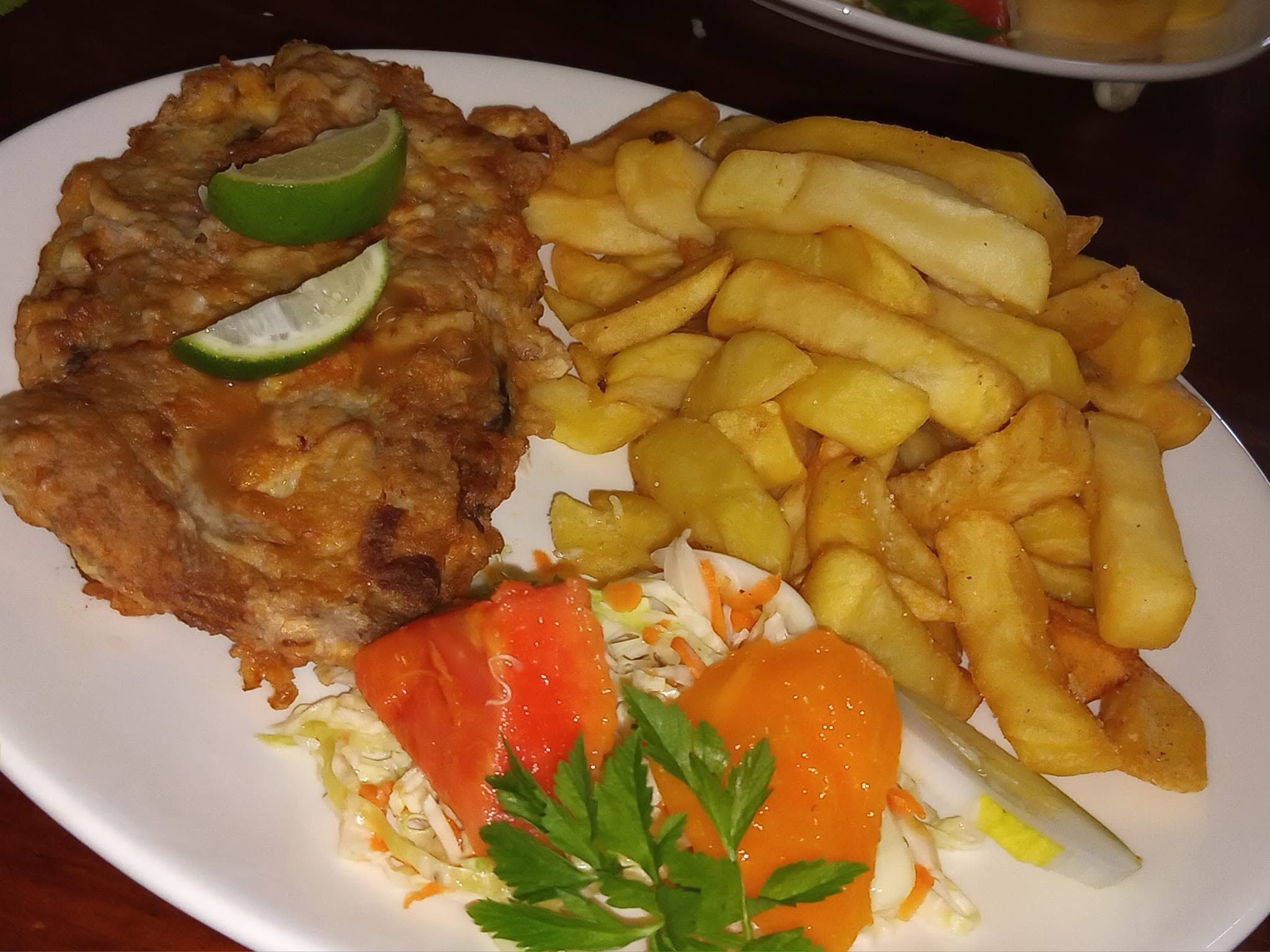 Breaded fish fillet served with thick-cut fries and fresh salad.