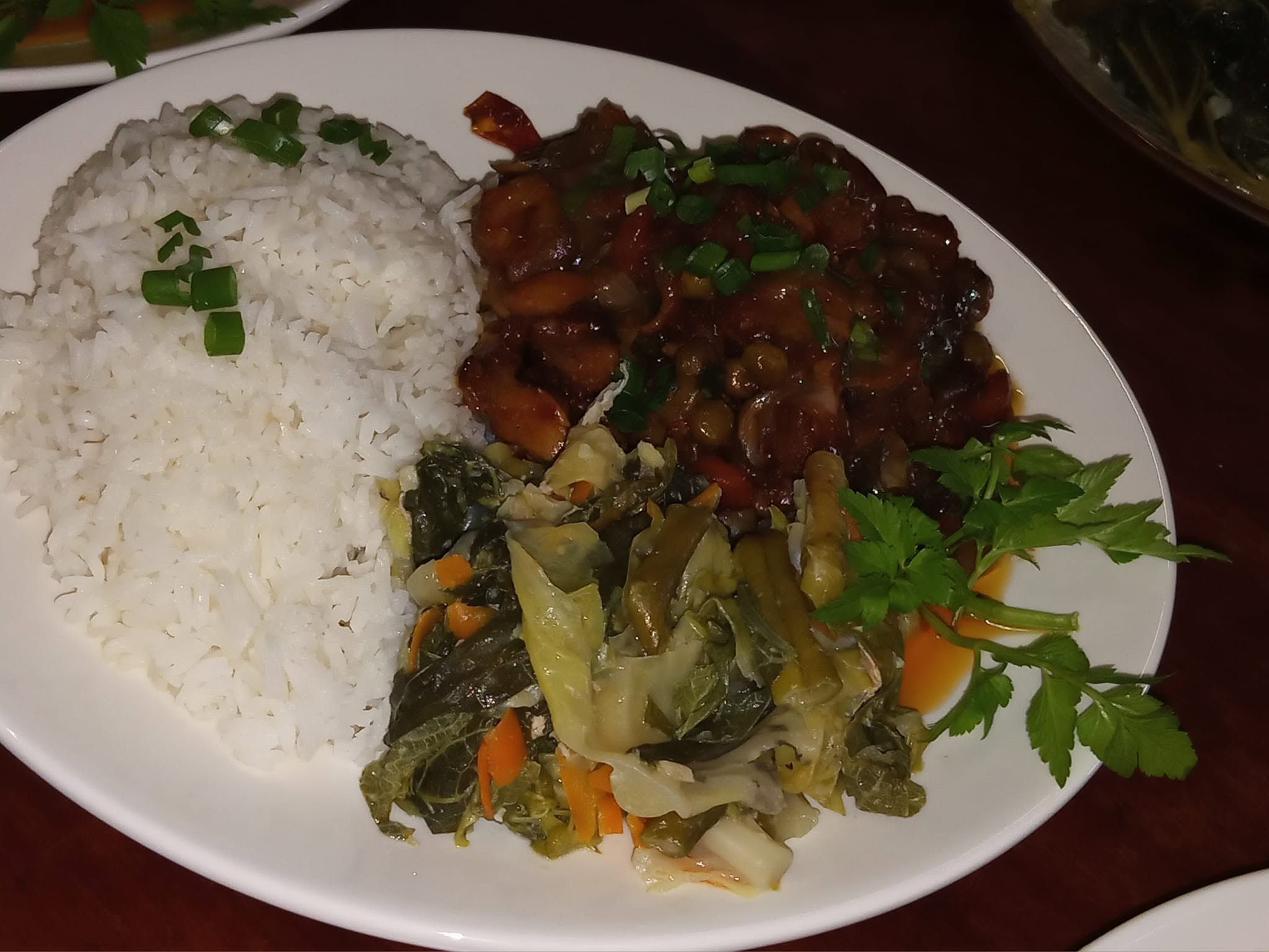 White rice served with stewed meat and sautéed leafy greens.