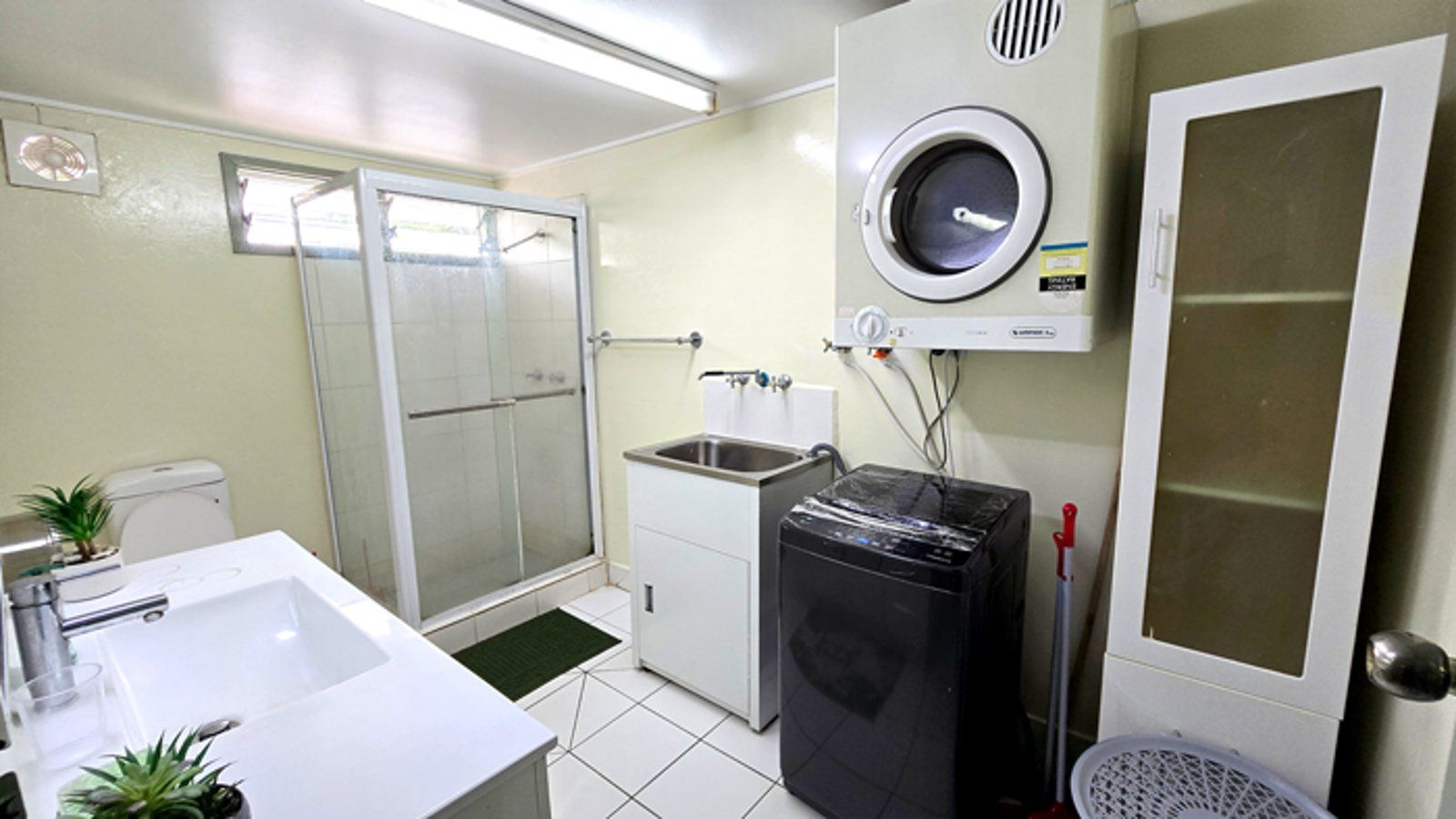 Bathroom and laundry area equipped with a shower stall and washing machine.