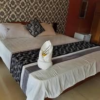 Double bed with decorative runner and folded towel art in guest room.