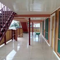 Brightly lit outdoor veranda with tiled flooring and red-painted pillars.