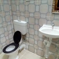 Tiled bathroom featuring a white porcelain basin and black toilet seat.