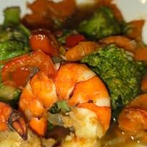 Close-up of a seafood dish with cooked prawns and broccoli.