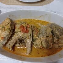 Fish steaks served in a cream-based sauce with tomatoes in a white dish.