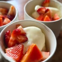Individual cups of fruit salad topped with yogurt and fresh strawberries.
