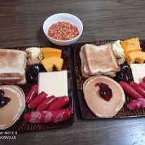 Breakfast platters with pancakes, toast, sausage, cheese, and jam.