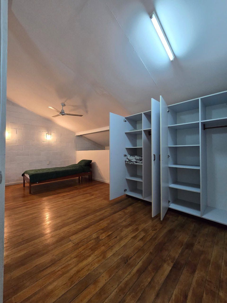 Spacious bedroom with polished wooden floors and large white storage cabinets.