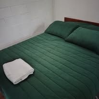 Close-up of a neatly made bed with green linens and a white towel.