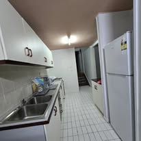 Functional kitchen area with white cabinetry, stainless steel sink, and refrigerator.