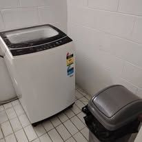 Laundry area with a top-loading washing machine and tiled flooring.