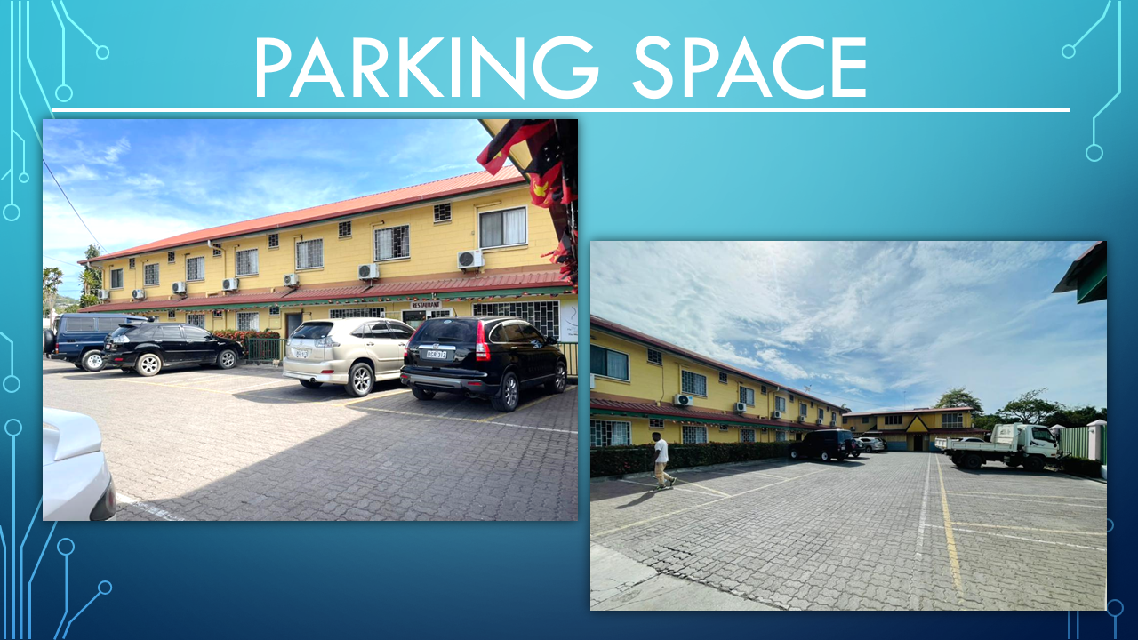 Spacious paved guest parking area in front of the yellow motel building.