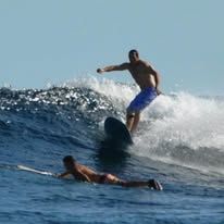 Surfers catching waves in the blue ocean waters near the resort.