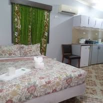 Guest room with double bed, green curtains, and attached kitchenette facility.